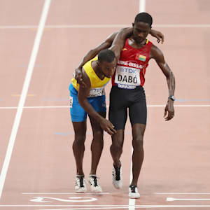 Braima Suncar Dabo helps Jonathan Busby to the finish line in their 5000m heat in Doha