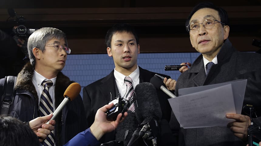 El nadador japonés Tomita Naoya (centro) habla con los medios durante su juicio por robar la cámara de un periodista en Incheon 2014  