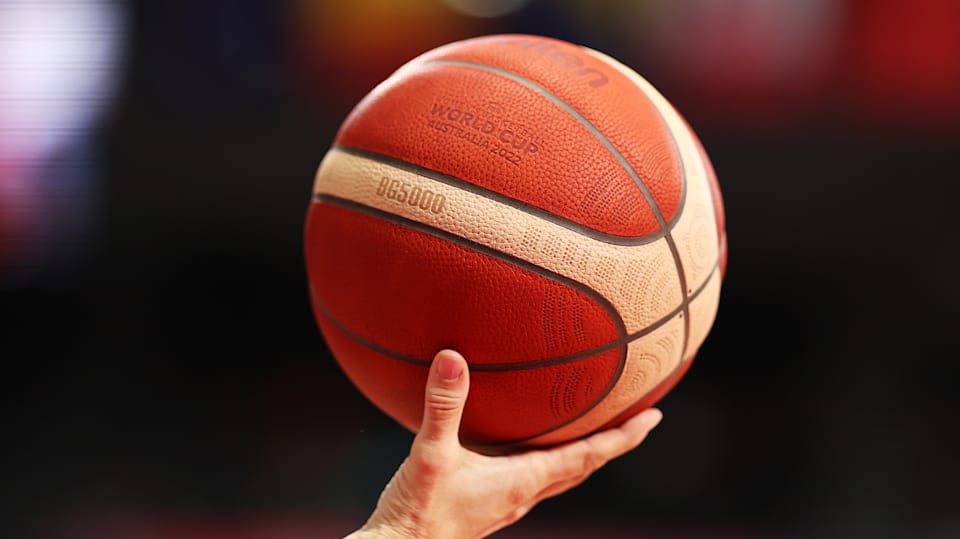 Un árbitro sostiene en alto el balón de baloncesto, FIBA 2022